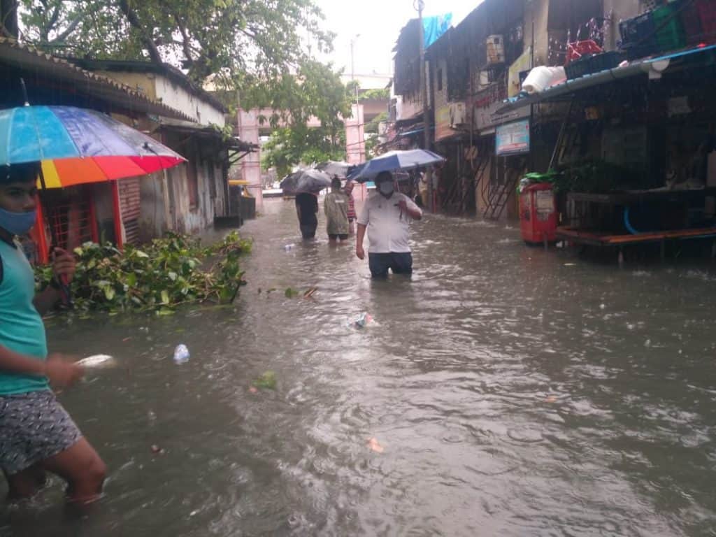 man walking in knee-deep water in mumbai