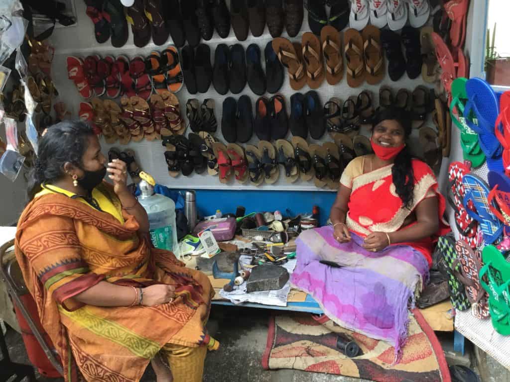 Woman repair cobbler at her workspace on the footpath with a customer