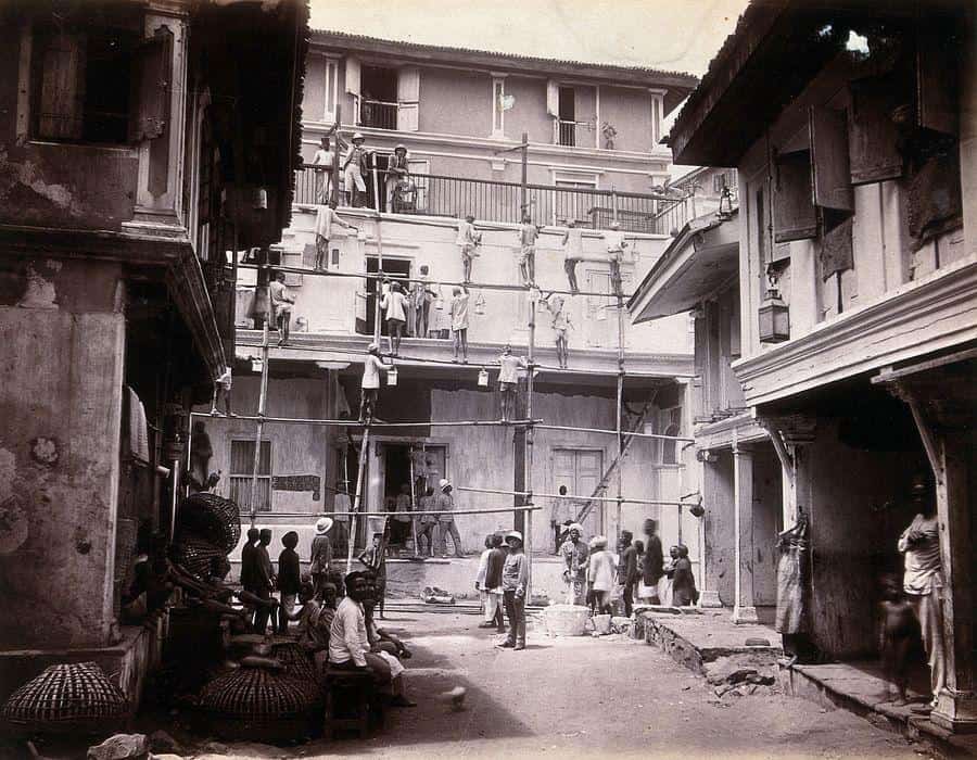 A black and while image of a building being painted white in 1896 Bombay
