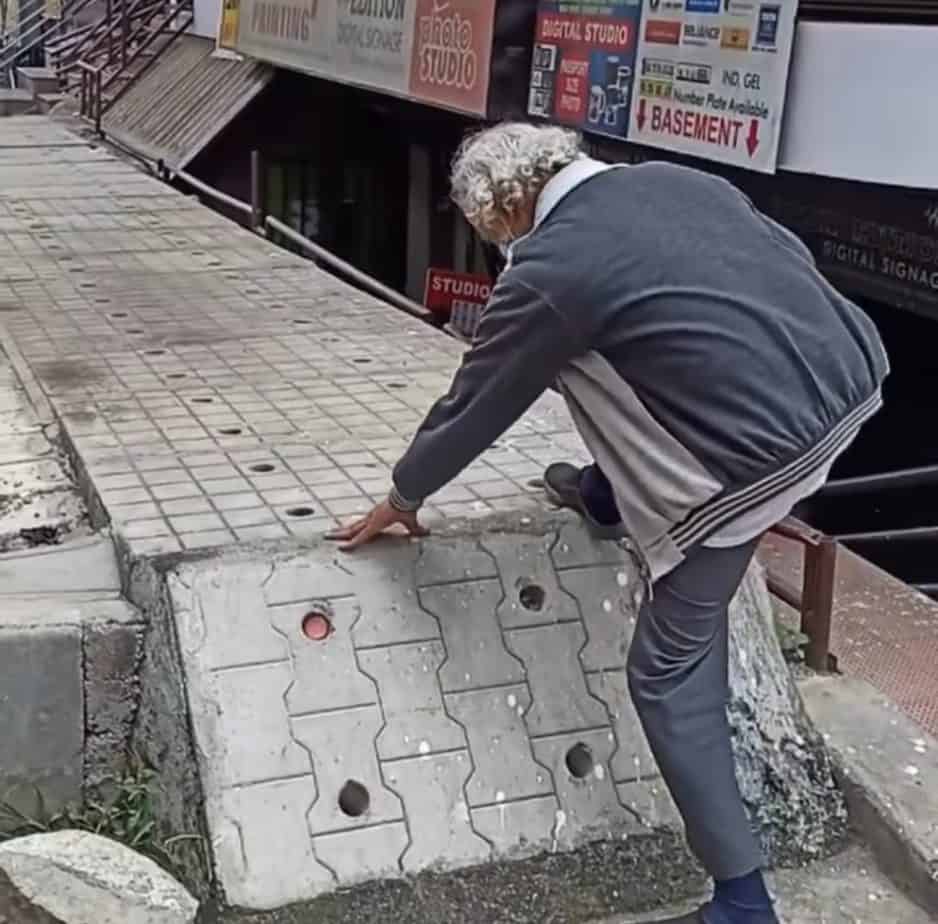 a senior citizen struggling to climb on a footpath