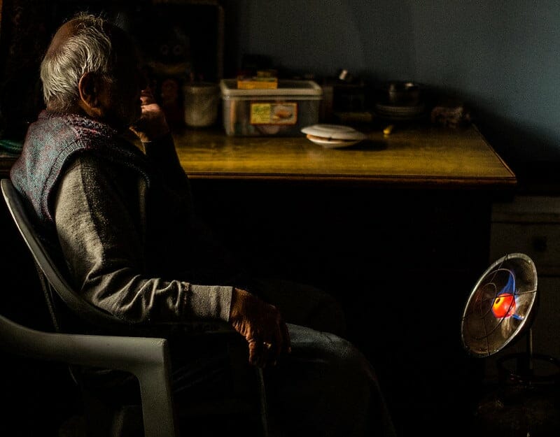 silhouette of an old man siting by a fan in silence