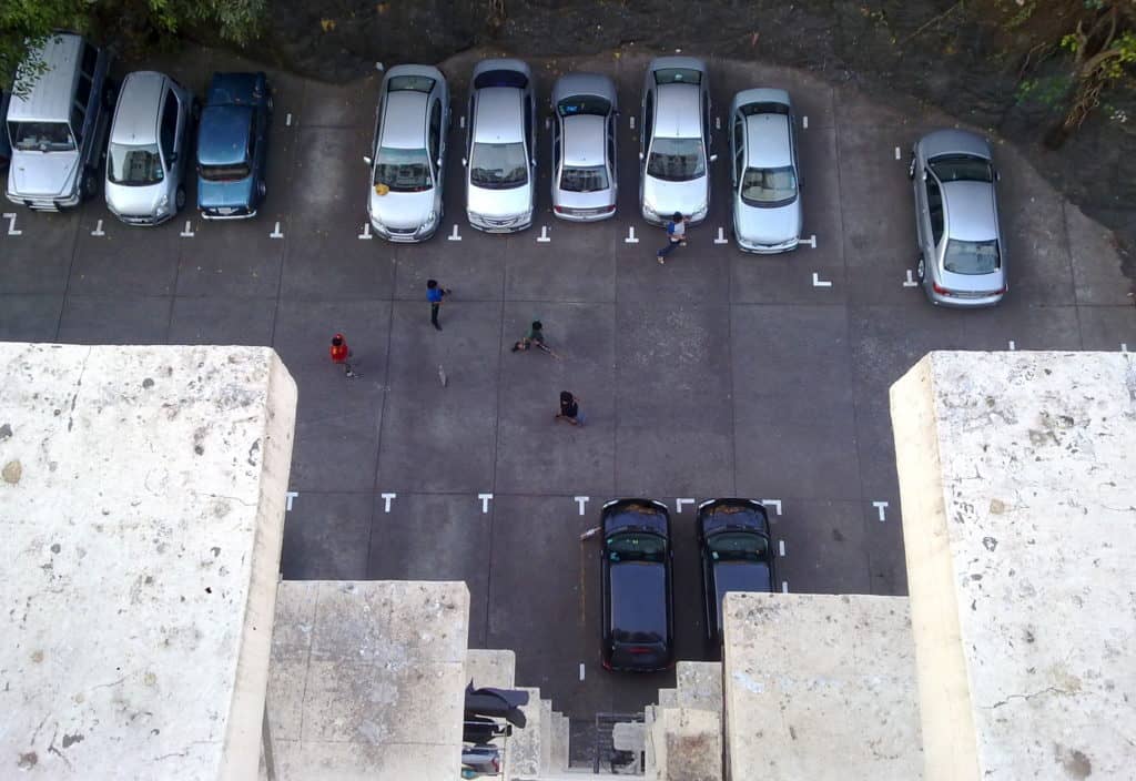children play cricket at a parking lot since mumbai has less open spaces available