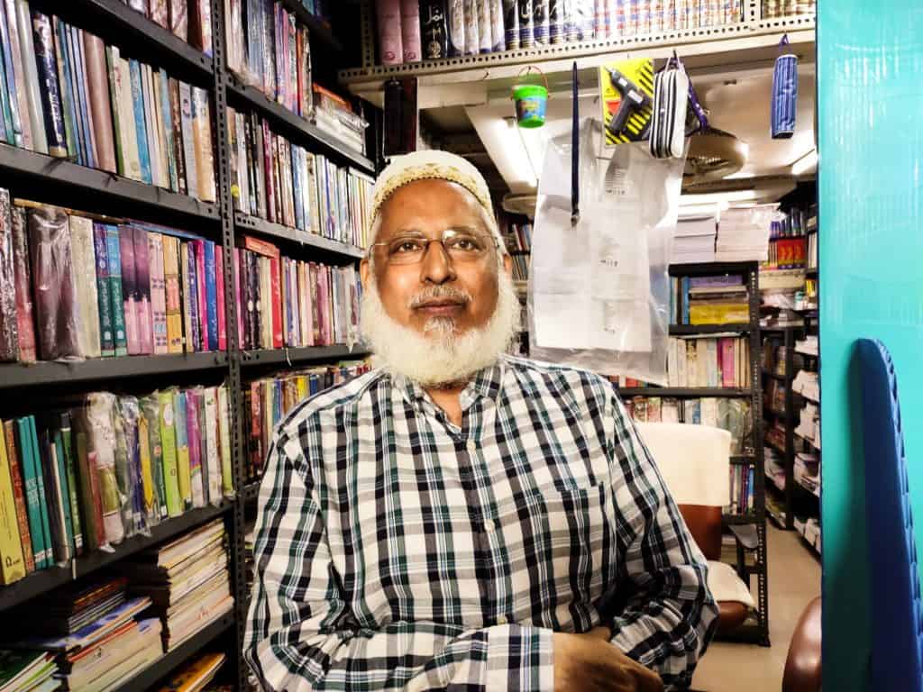 Portrait of a book shop owner, posing with his large collection of books