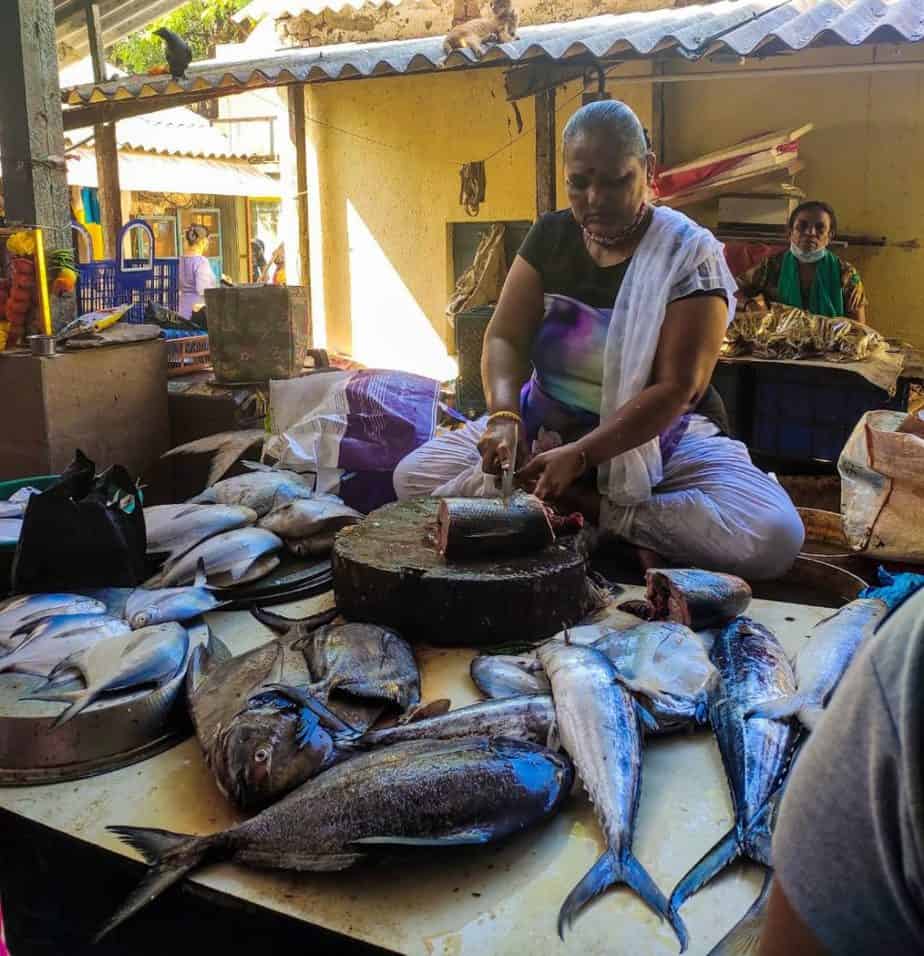 fisherwoman cutting fish to sell to customer