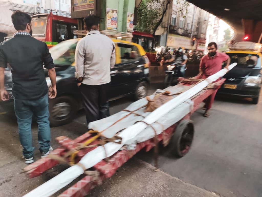 A hand cart on the main road in the middle of peak traffic.