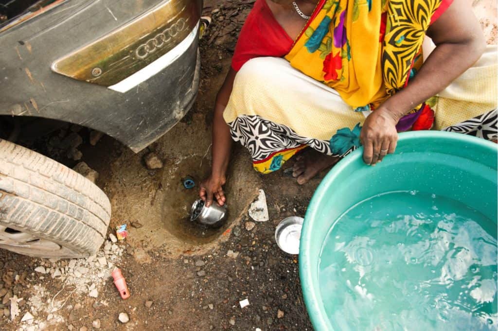 Woman filling water from a broken pipe in Mumbai