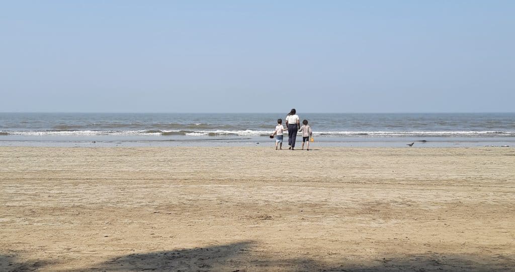 A mother at an empty beach with her two children