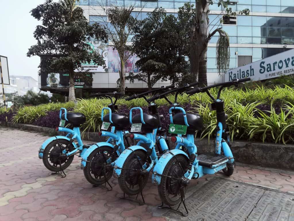 A row of blue moped bikes parked on a footpath 