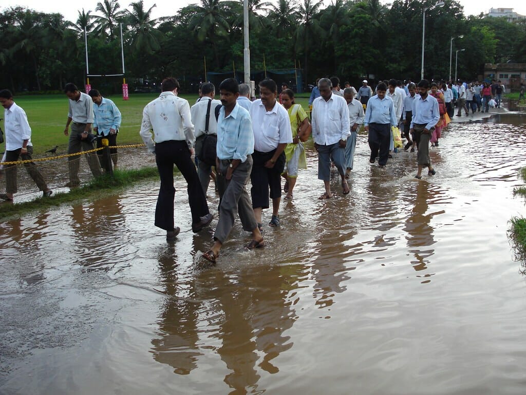 crowds of people walk through a flooded Azad maidan in 2007