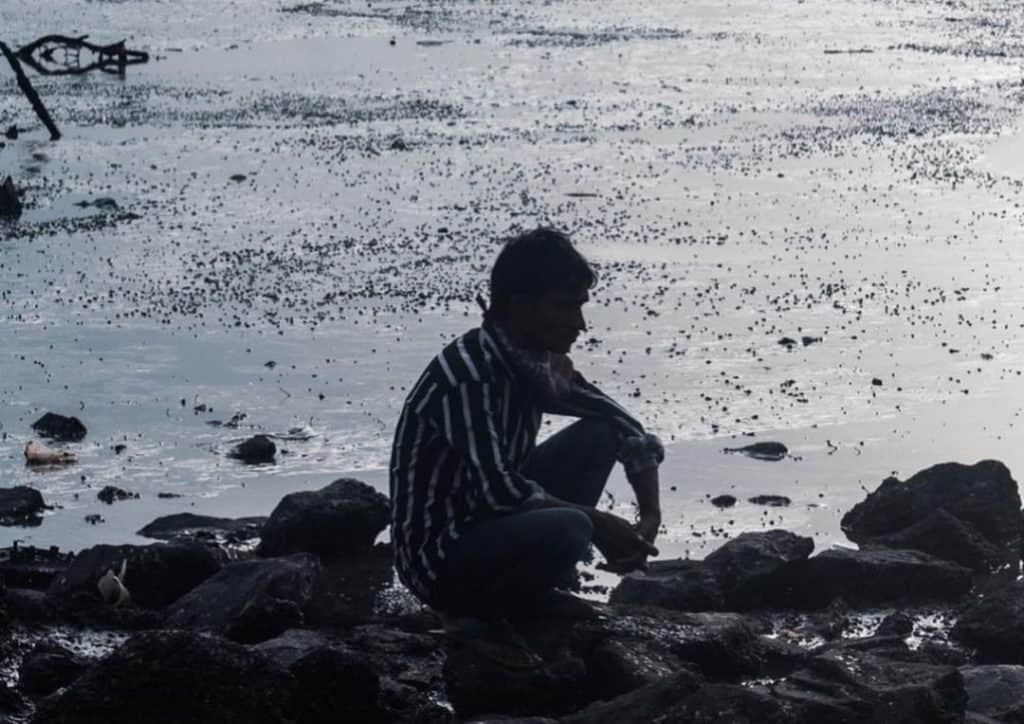 Man sitting by the shore of Versova in Mumbai