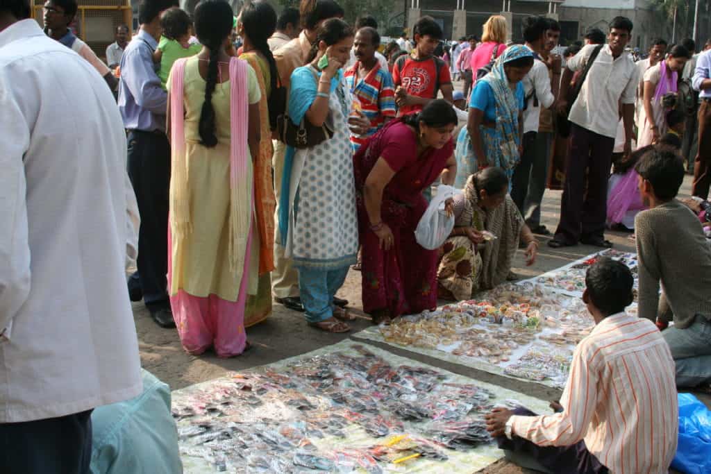 Hawkers selling accessories and tools on a mat on the floor of the road