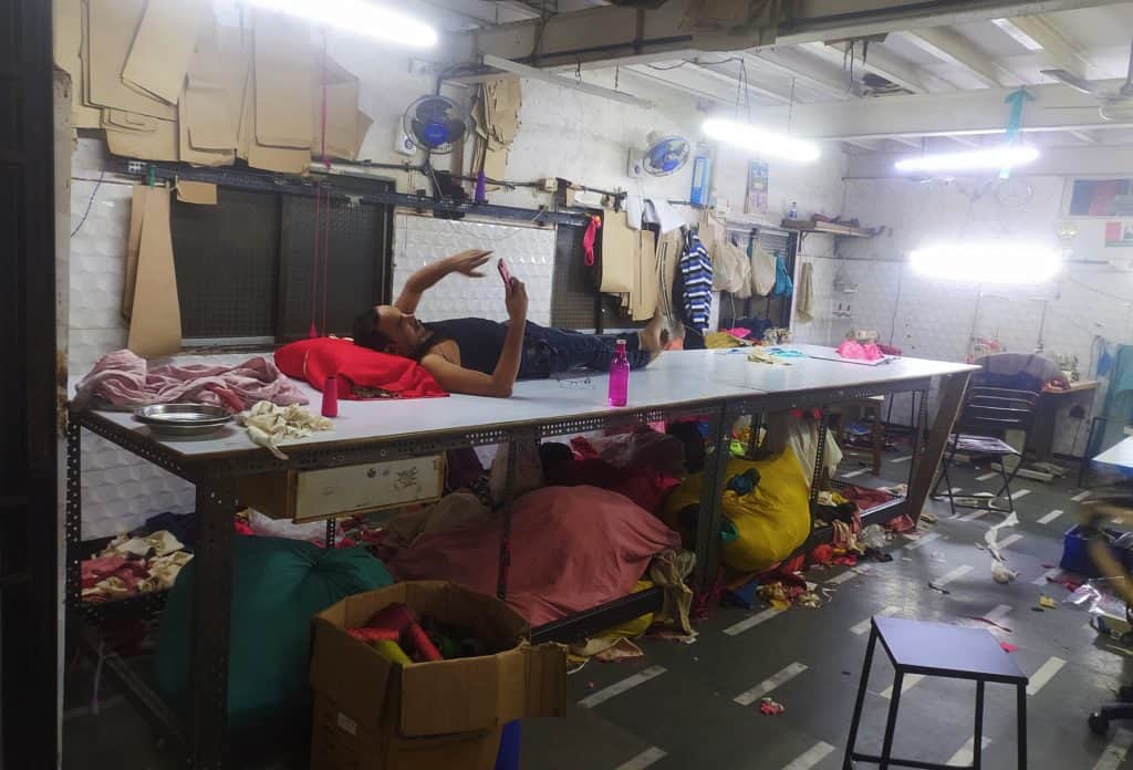 a garment worker in Dharavi taking a break on top of a table where he works