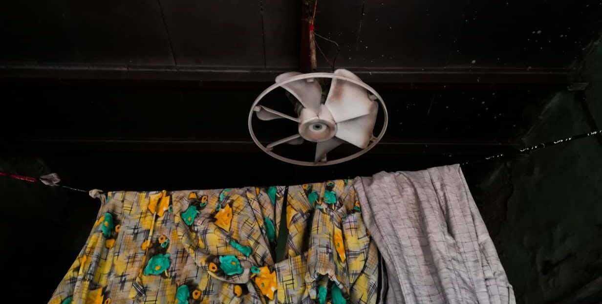 An atypical cieling fan in an house over a washed clothes hanging rope