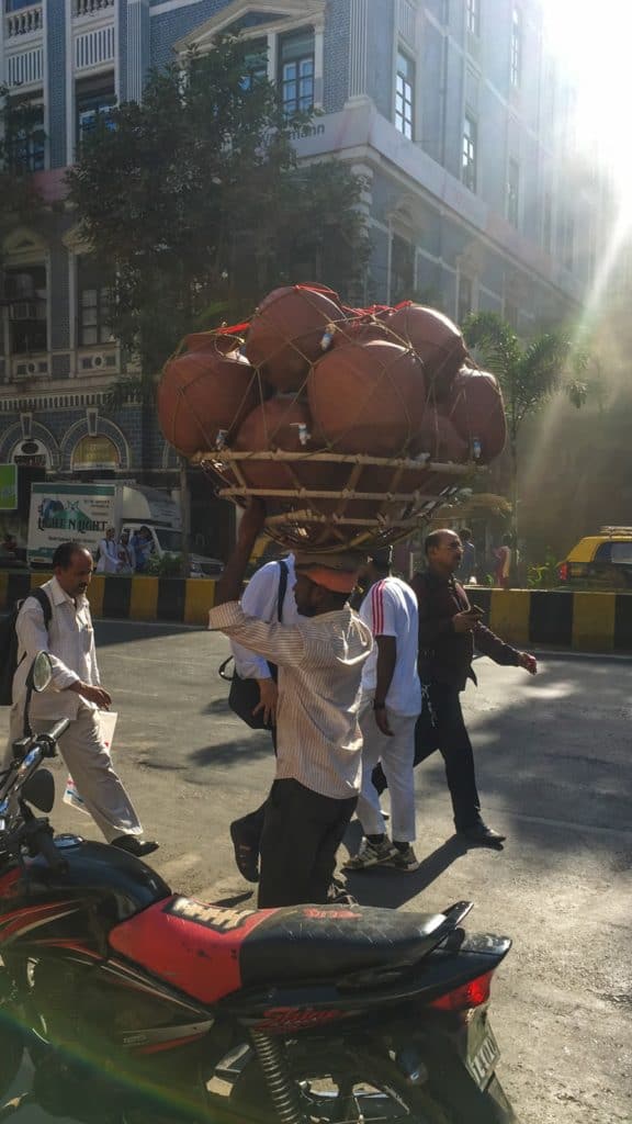 a man in mumbai carries clay water dispensers on his head on a road