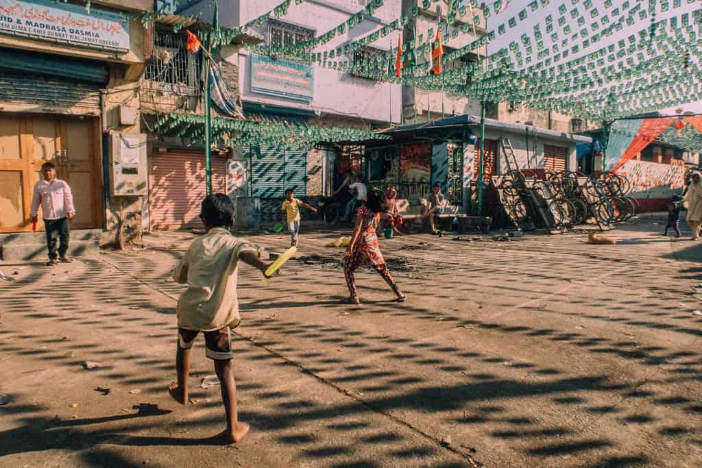 Children playing out in the open with the small shadows over them, unbothered by the urban heat