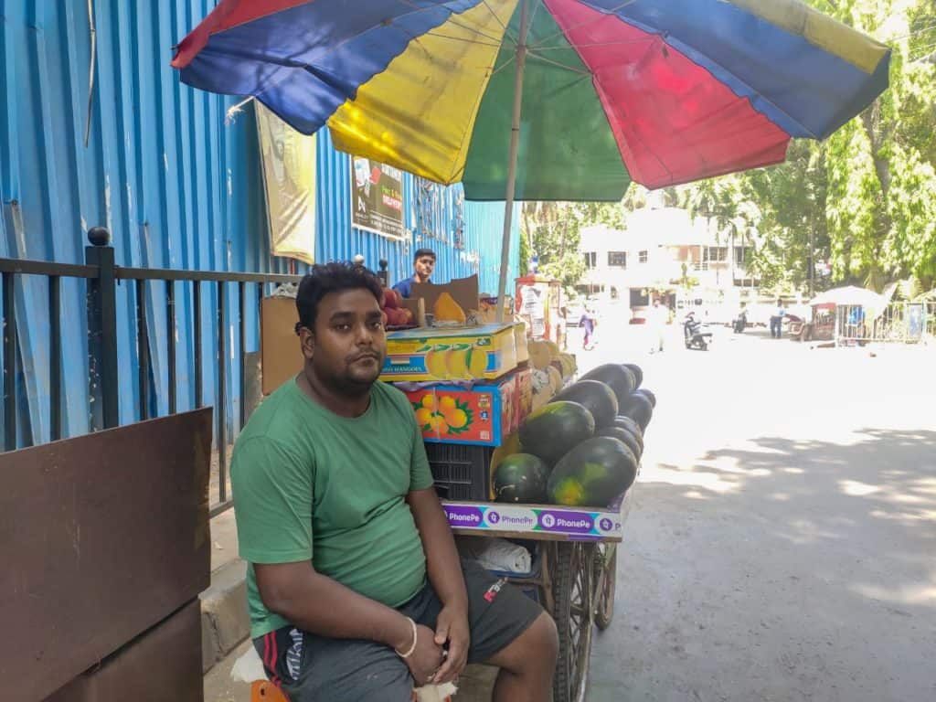 vendor sitting in front of his fruit cart
