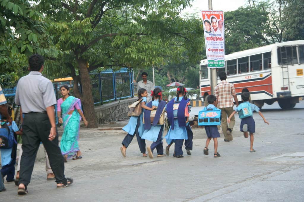Kids in school uniform running towards their bus on the road