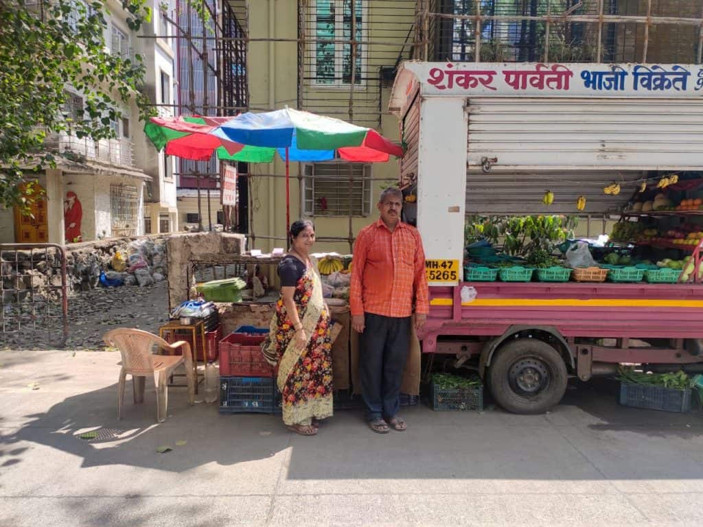 vegetable vendors pose for a photo outside of their tempo.