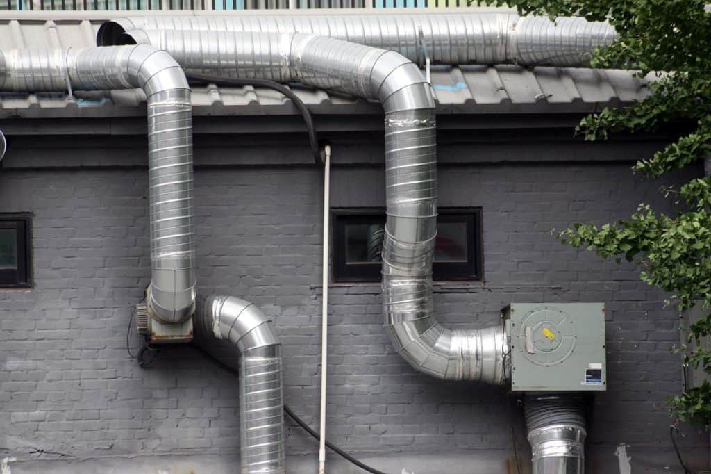 Two metal pipes for ventilation placed beside a wall show Ventilation system of an STP