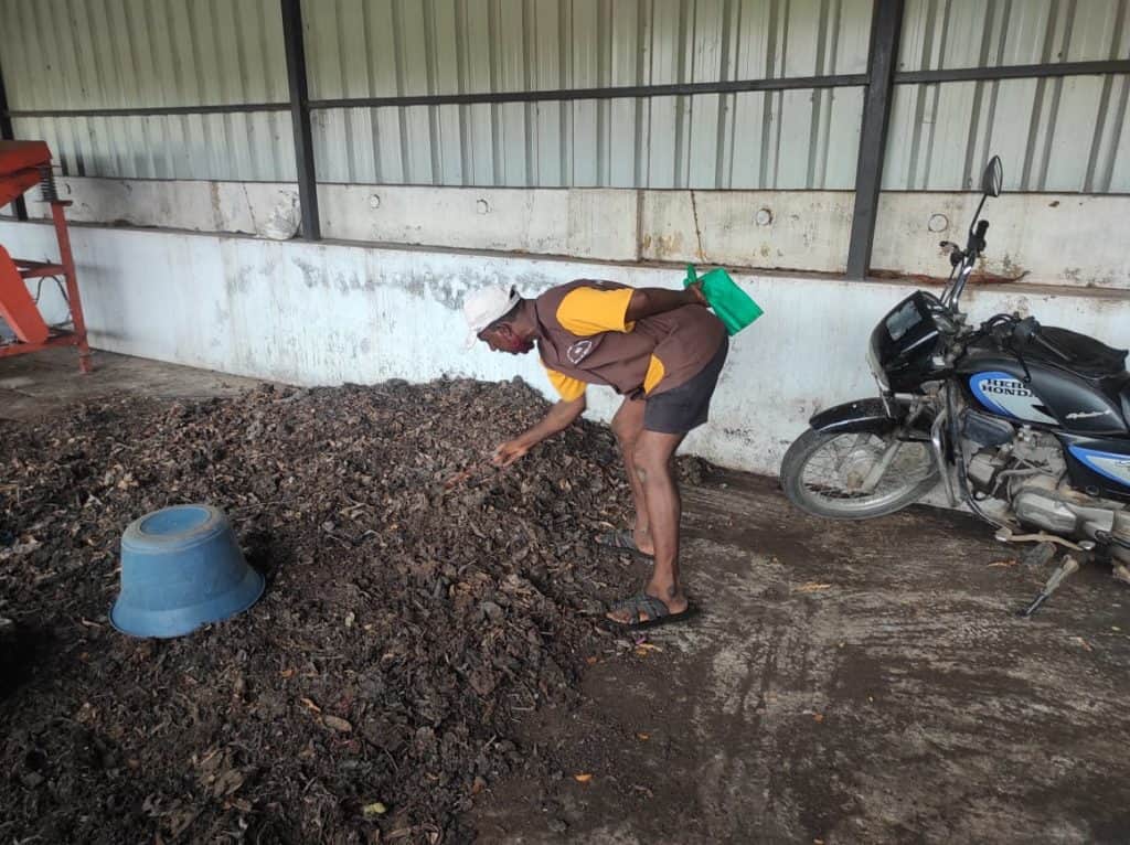 Worker drying the compost in South Cooum Road micro composting centre