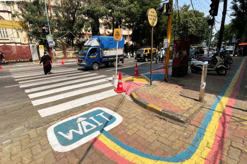colourful strip marks walking zone and ends in a sign that reads 'Wait' so students know to look at the signal.