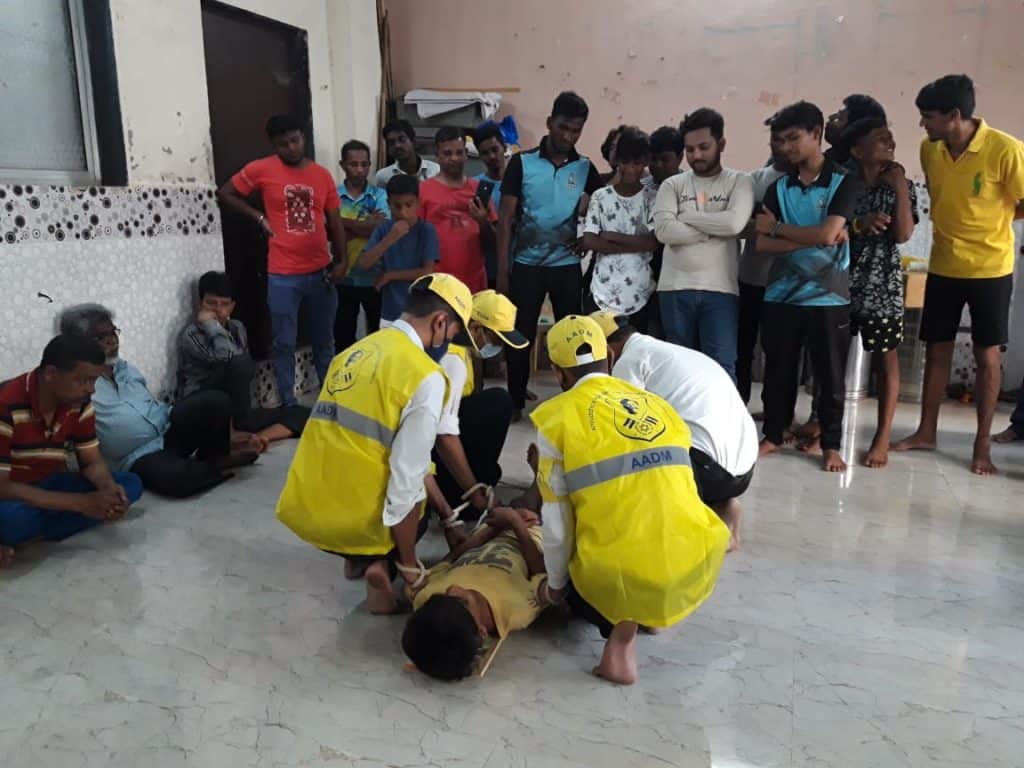 People teaching a group how to carry a stretcher in emergency situations for monsoon preparedness