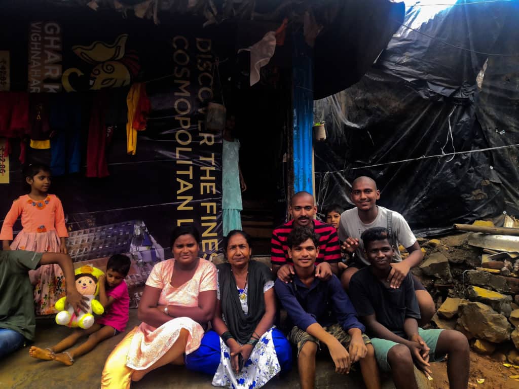 People posing for a photo in front of a informal impermanent house in the Kranti Nagar slum.