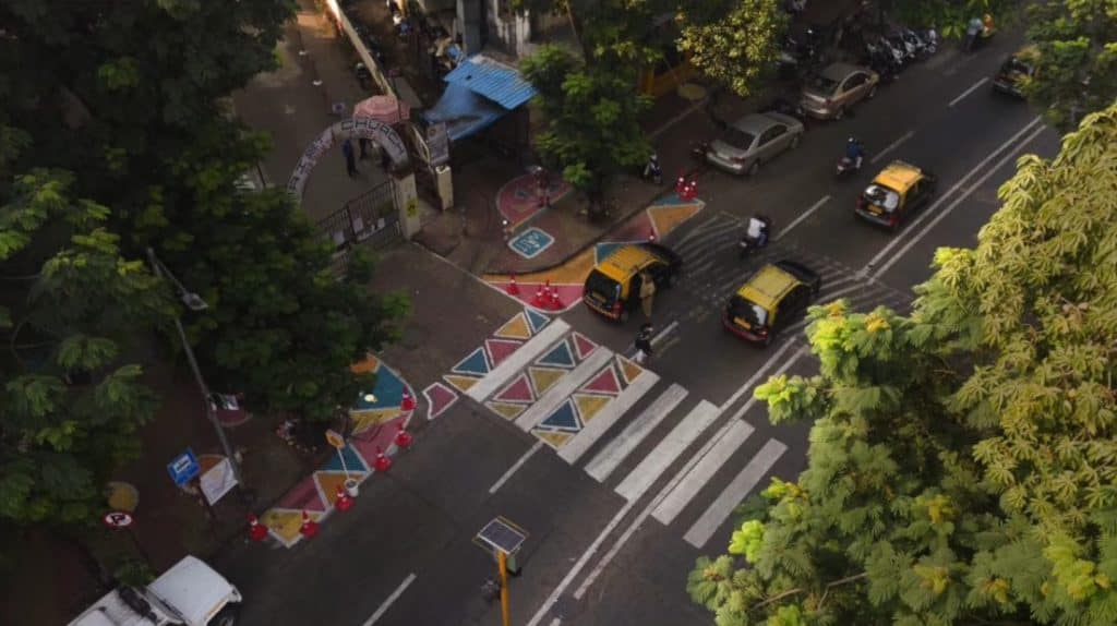 An overview of the outside of a school gate, with colourful zebra crossings and waiting spots for safety as a trial under tactical urbanism. 
