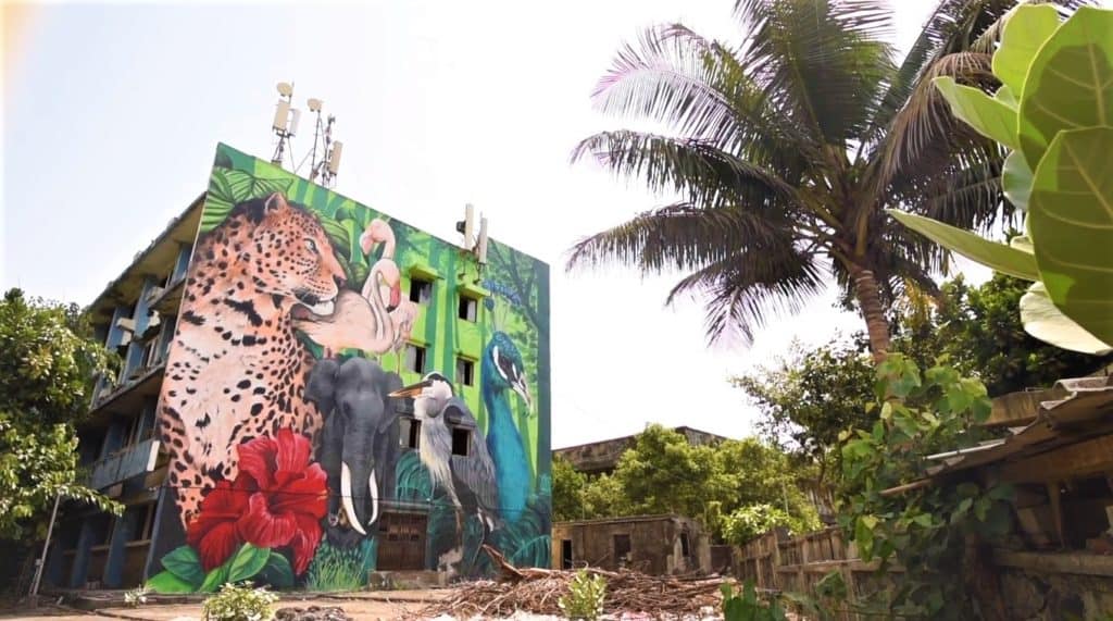 One side of a building with a jungle mural painted, with tigers, flamingoes, elephants and other animals.