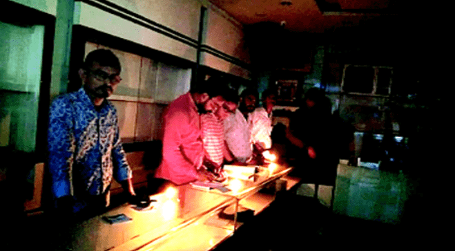 6 men in the jewellery shop 'umedmal tilokchand zaveri' working under candle light.