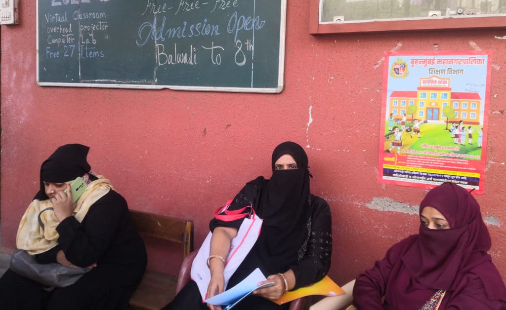 3 women in hijab sitting at a bench in the RTE verification centre