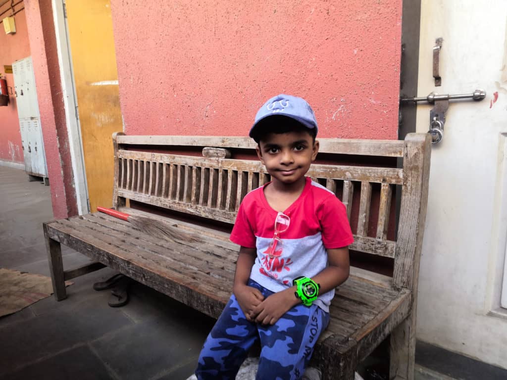 A small boy sitting on a wooden bench