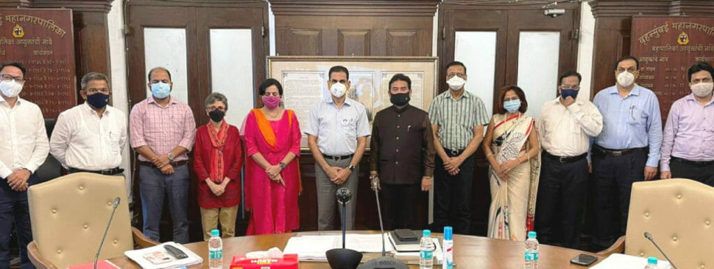 People in masks standing in a row behind a table