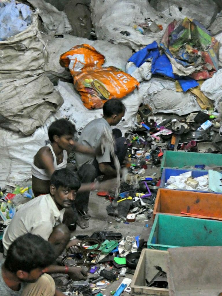 Workers sitting in front of colourful boxes in a waste segregation centre segregating difference kinds of recyclable material