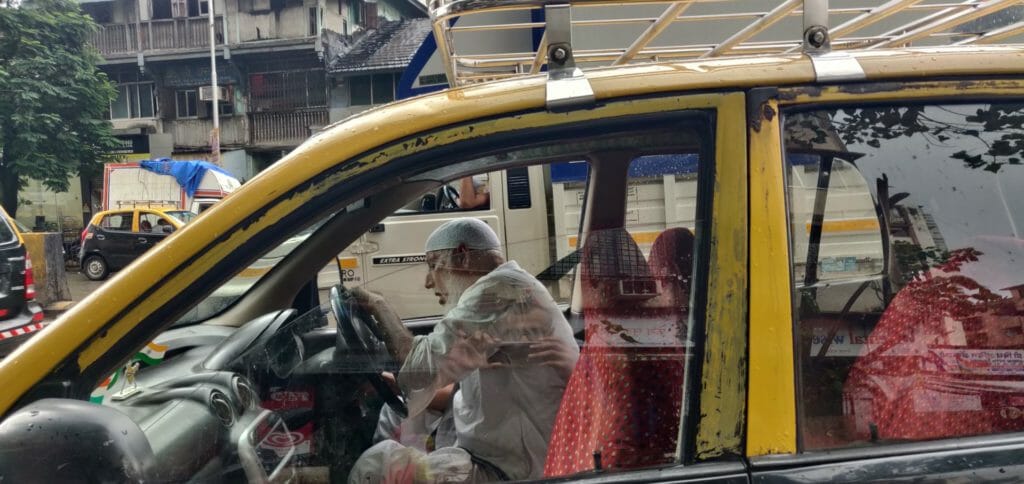 Sain Ullah Khan is sitting in the driver's seat of a black and yellow taxi.