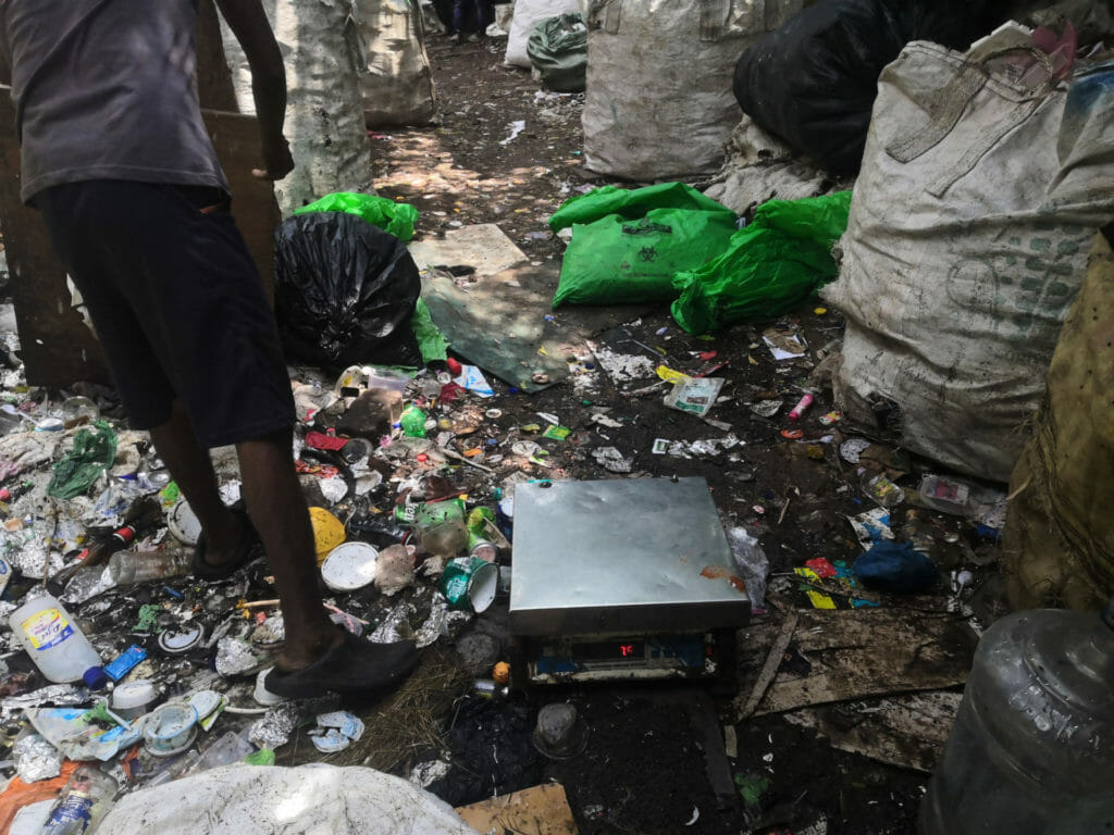 A weighing scale set on the ground amidst waste scattered around