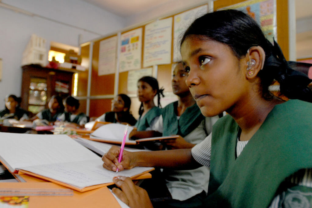 Representational image of a girl child in class, wearing a hearing aid.
