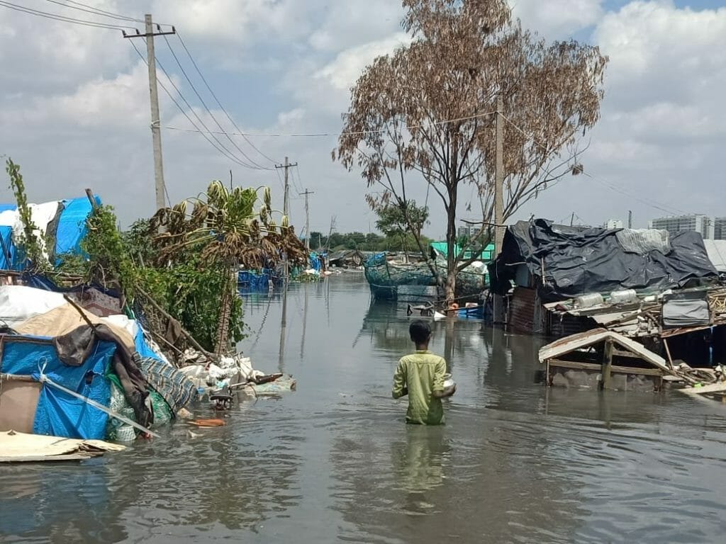 Residents wade through waist-deep water after settlement floods in Bellandur