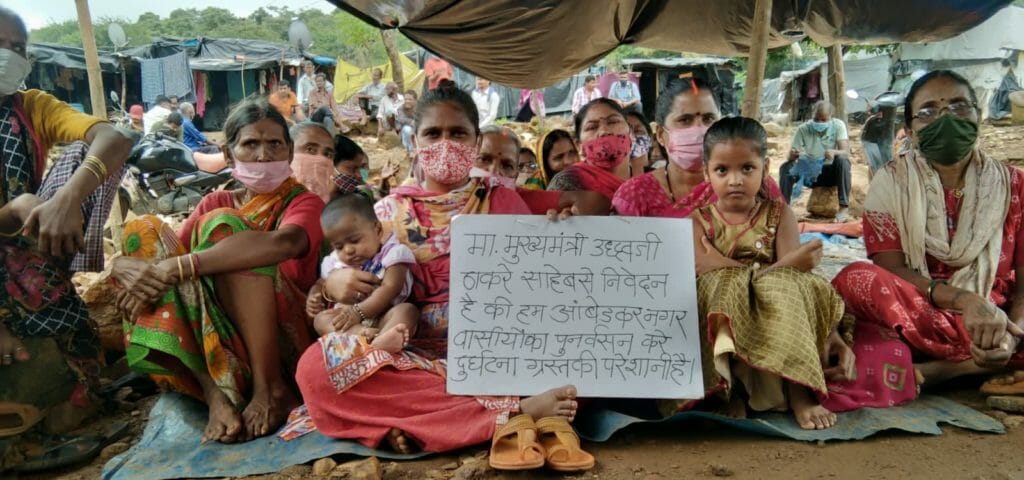 Victims of the landslide in Malad sit with a placard protesting
