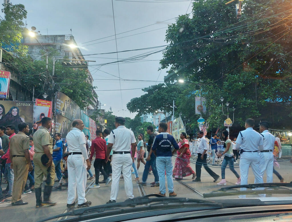 Police and volunteers help people cross the main streets of Kolkata during Durga Puja