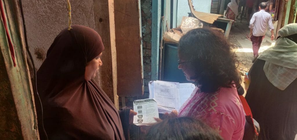 Sunita Sutar is conducting TB and leprosy survey by showing a pamphlet, which contains information on leprosy, to a respondent.