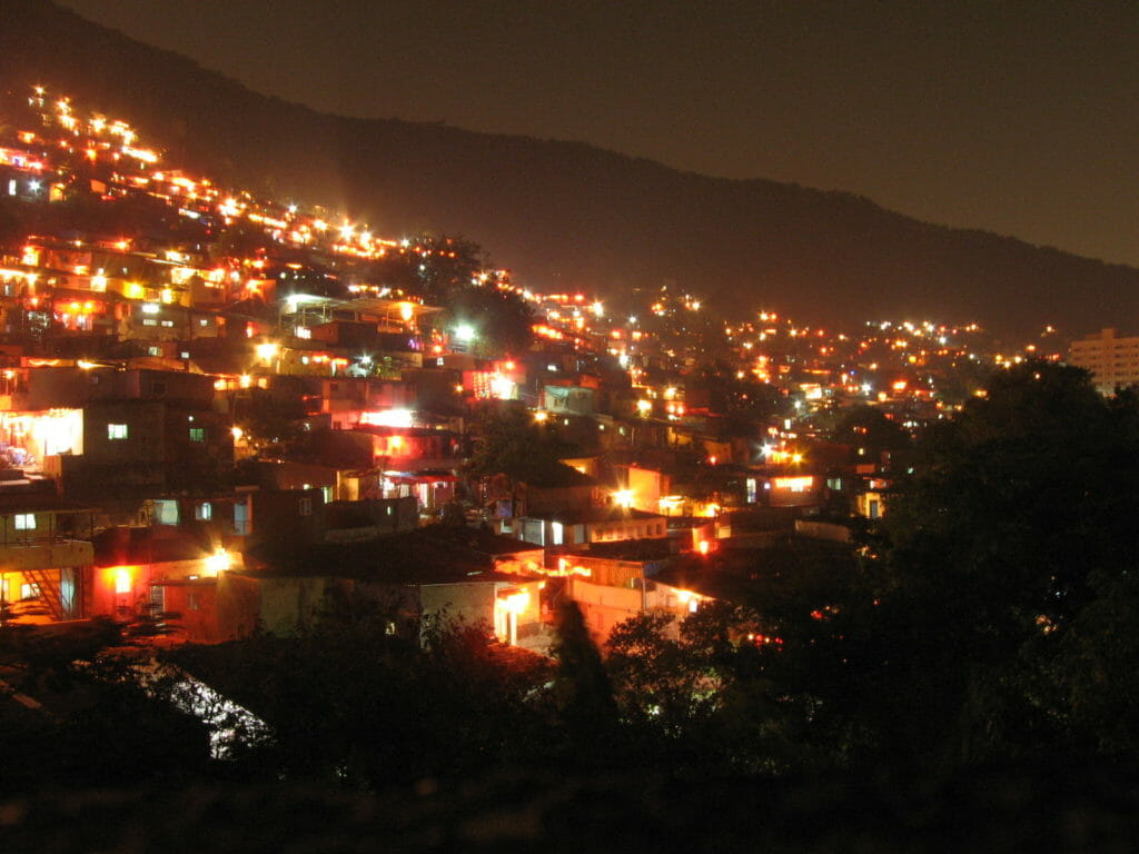 Slums on a hillside at night with shining lights