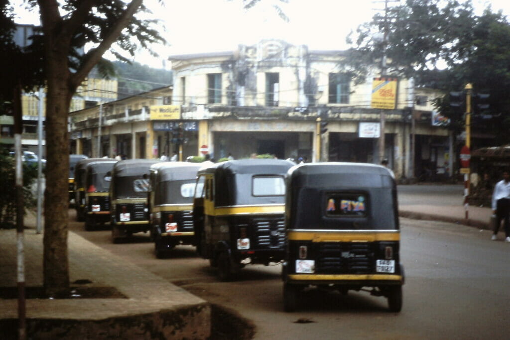 Autos parked by the side of a street in a city in Goa