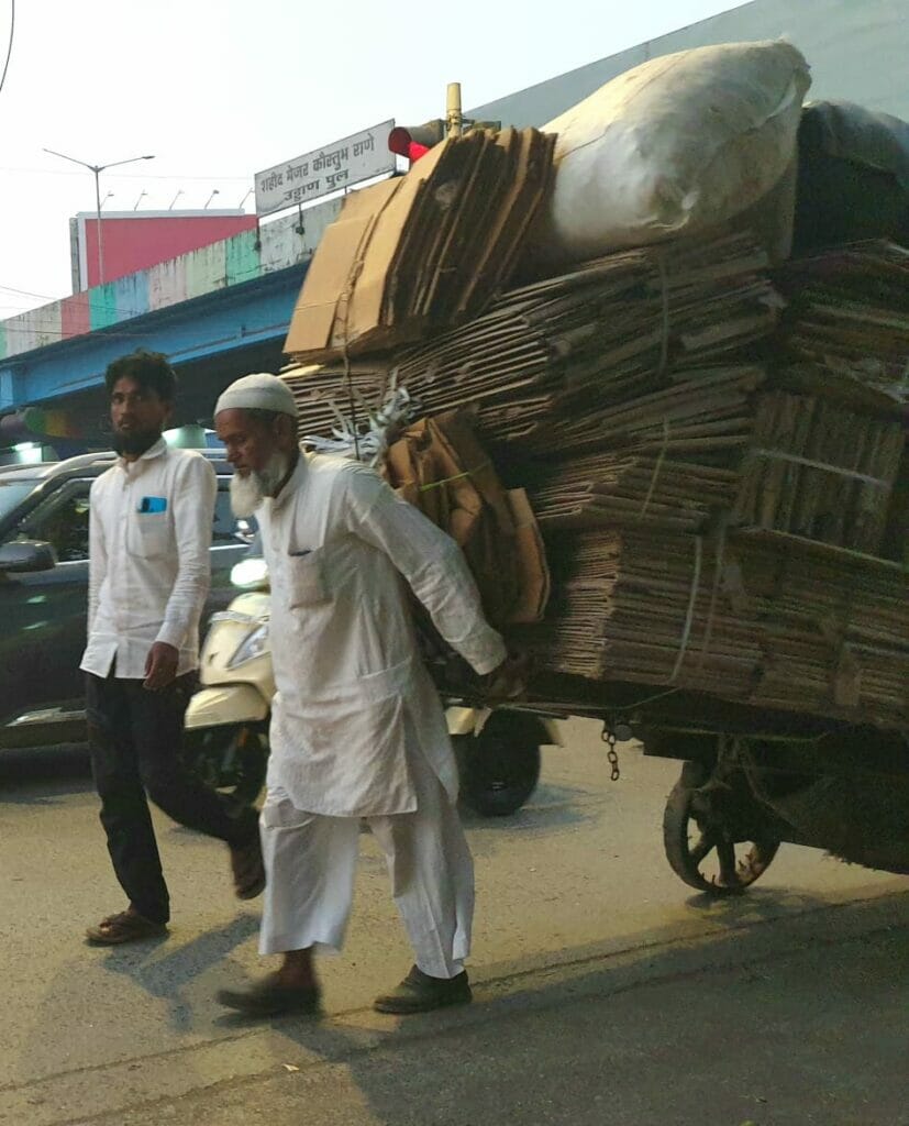 Old man pulling a handcart loaded with scrap cardboard