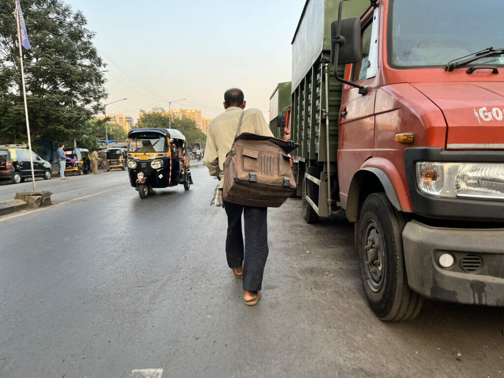 man walking on the road with a bag on his shoulder