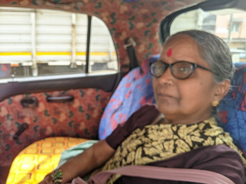 Shakuntala sitting by the window in a taxi with a seatbelt.