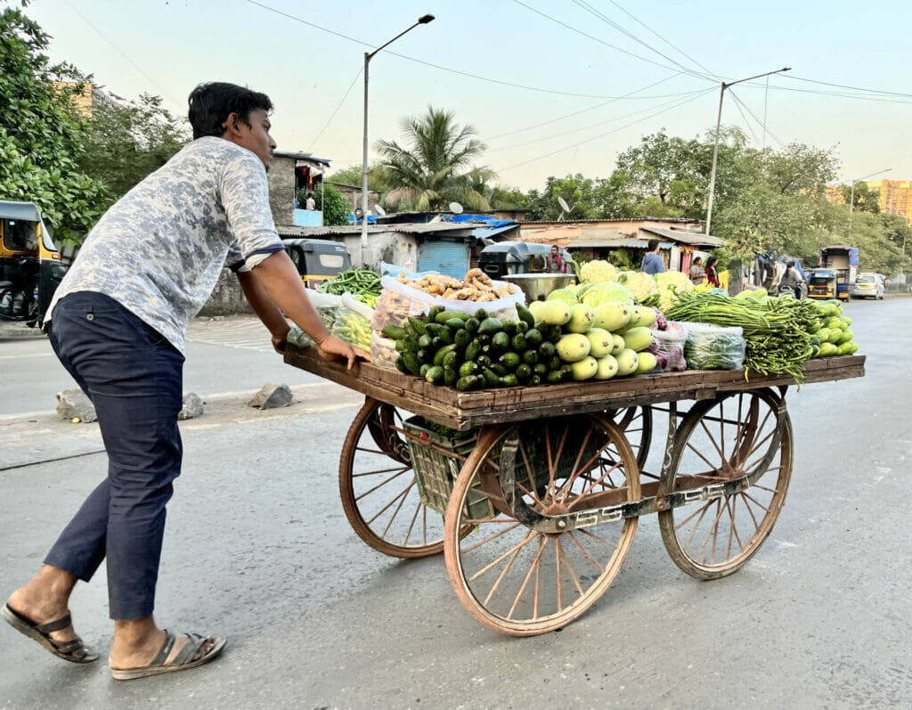 vegetable vendor pushing a handcart loaded with vegetables