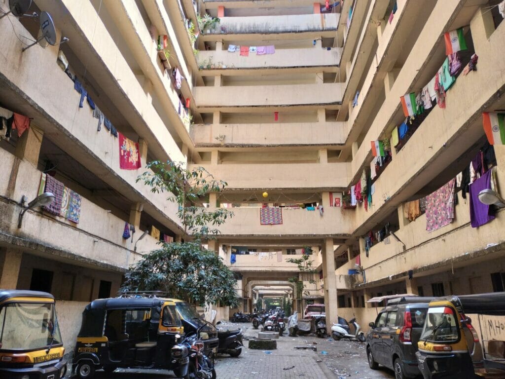 A view of the hollow clearing of the building, with parked bikes and rickshaws around. 
