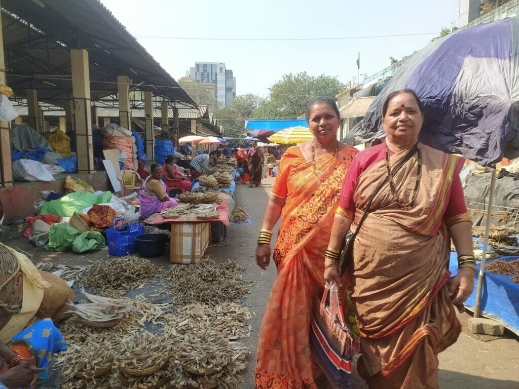 Koli fisherwomen walk through a dried fish market