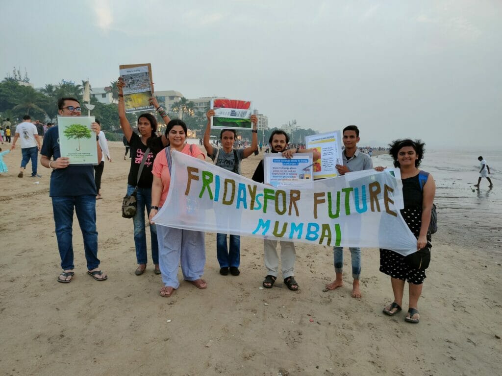 group of people at a beach holding a banner that says 'Fridays for Future Mumbai'